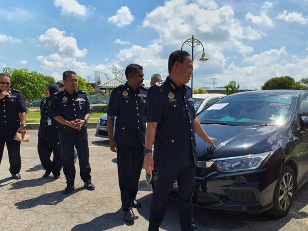 Adenan menunjukkan kenderaan pemandu e-hailing yang disita selepas dikesan menggunakan aplikasi haram.