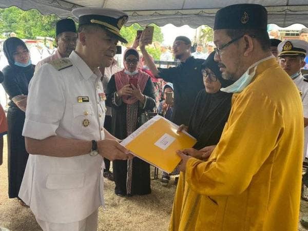 Sharum (kiri) menyampaikan sumbangan dan watikah takziah daripada Yang di-Pertuan Agong kepada ibu bapa Muhammad Arif.