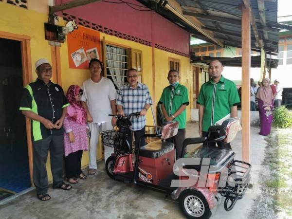 Tengku Hassan (tengah) ketika menyerahkan motosikal elektrik kepada Shahriman dan isteri, Samsu Yanti di rumah sewa mereka di Taman Jaya, di sini.