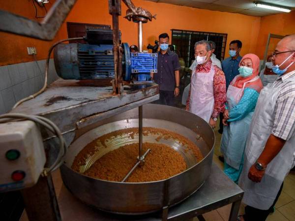 Muhyiddin (tengah) dan isteri (tiga dari kanan) melihat proses membuat perencah nasi goreng kampung semasa mengadakan lawatan ke De Muara Enterprise di Bukit Gambir hari ini. - Foto Bernama