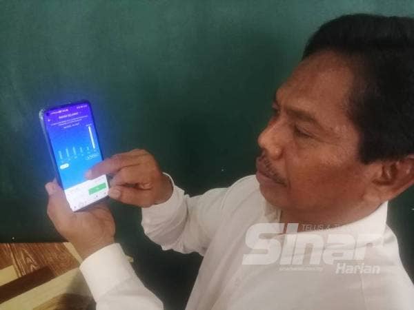 Rahim menunjukkan caj semasa TNB di telefon bimbitnya.