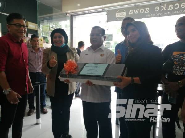 Ahmad (tiga dari kiri) menyampaikan cenderahati kepada Eravaizura Salleh (kanan) sempena program Jelajah Agropreneur Muda di Ayer Keroh.