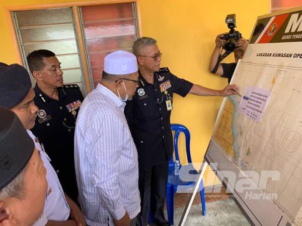 Hasanuddin menunjukkan lokasi kejadian kepada Ahmad semasa tinjauan di jeti Kuala Kemasin di sini.