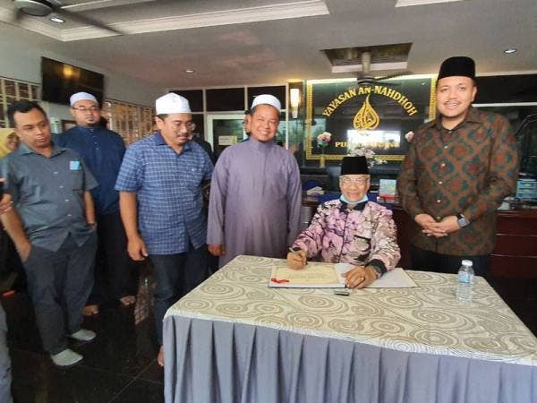Mansor mengisi buku tetamu ketika mengadakan lawatan kerja di Yayasan An-Nahdhoh hari ini.