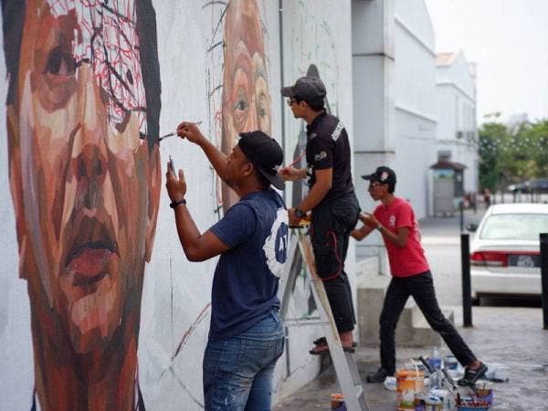Muhammad Suhaimi (kiri) bersama dua rakannya, Firdaus Nordin (tengah) dan Abdul Hadi Ramli menyiapkan mural di Seksyen U12, Desa Alam, Shah Alam, Selangor.