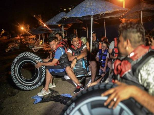 Gambar fail menunjukkan beberapa orang imigran duduk di tepi pantai Bodrum, Turki. - Foto AFP