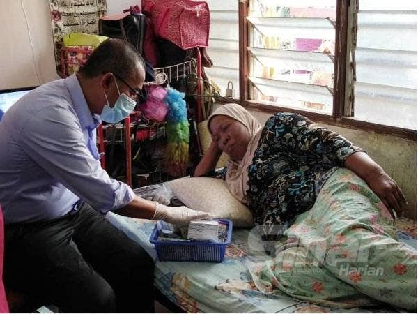 Dr Noor Azmi (kiri) bertanya khabar ketika melawat Rauziah yang menghidap kanser di Felda Chini 5, Pekan hari ini.