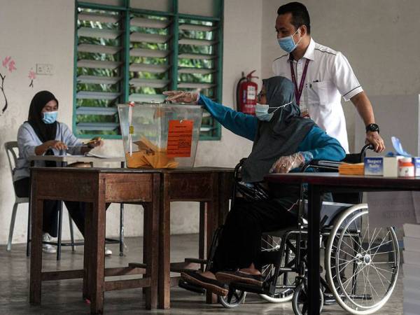 Pengundi, Mariam Abdullah, 59, dibantu petugas Suruhanjaya Pilihan Raya ketika mengundi pada Pilihan Raya Kecil (PRK) Dewan Undangan Negeri (DUN) Chini di Kelas Al-Quran dan Fardu Ain (KAFA) Felda Chini 3 hari ini.