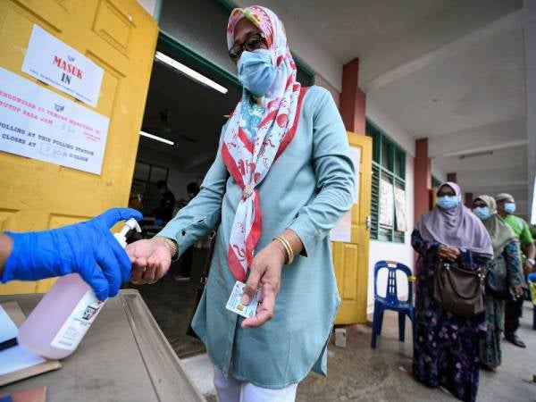 Pengundi kelihatan menggunakan pembersih tangan (hand sanitize) sebelum mengundi pada PRK DUN Chini di Kelas Al-Quran dan Fardu Ain (KAFA) Felda Chini 3 hari ini. - Foto Bernama