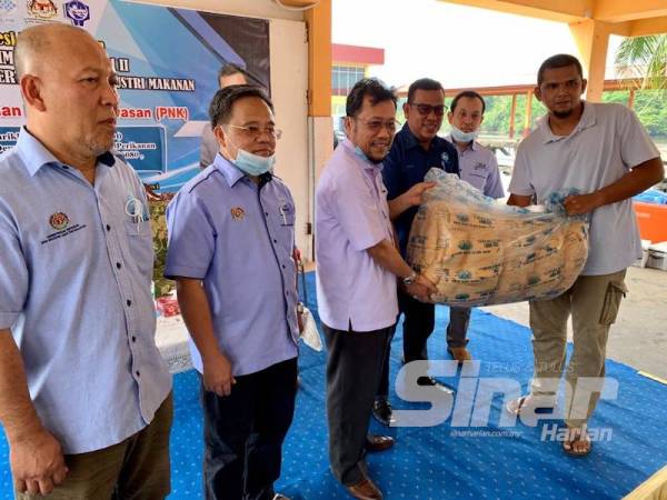 Che Abdullah (tengah) menyerahkan pukat kepada salah seorang nelayan menerusi Program Rezeki Tani di Kompleks LKIM, Tumpat hari ini.