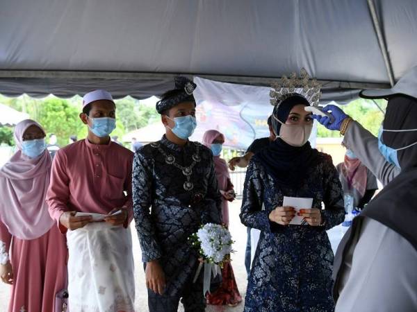 Abdul Rahim Idris (dua, kiri) dan pasangannya Ainul Aqilah Abdul Rahim (kiri) dan Siti Hajar Idris (dua dari kanan) dan pasangannya, Muhammad Aizat Zulkifli (tiga dari kanan) diperiksa suhu badan sebelum memasuki pusat mengundi di Kelas Al-Quran dan Fardu Ain (KAFA) Felda Chini 3 hari ini.
Foto: Bernama