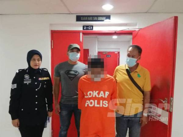 Suspek diiringi polis sewaktu hadir di mahkamah di Kuala Terengganu hari ini.