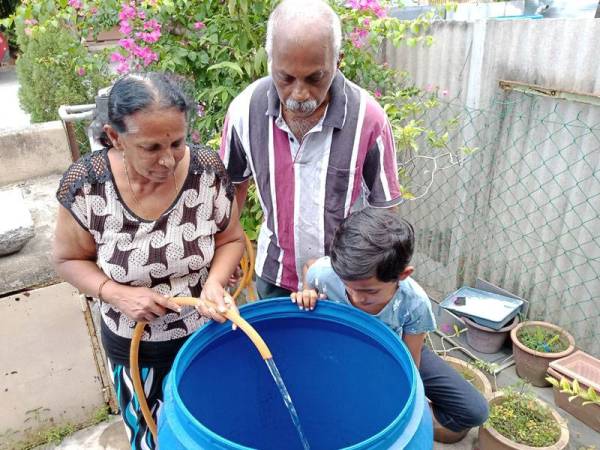 N.Thillai bersama isterinya sedang menahan air di dalam tong sebagai persediaan untuk menghadapi gangguan bekalan air bermula 14 Julai ini.