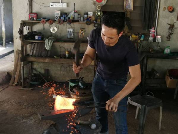 Lokman Nurhakim menyiapkan tempahan kapak yang diterimanya.