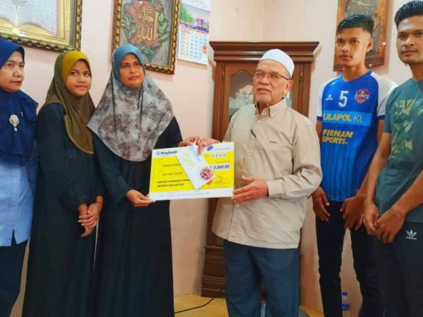 Rosni Wati (tiga dari kiri) bersama anak-anaknya menerima sumbangan daripada Perkeso dan Tabung Serambi Makkah yang disampaikan oleh Hanifa (tiga dari kanan) dan Nora (kiri) di rumahnya di Kampung Padang To’ La di sini hari ini.