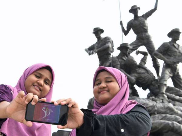 Pasangan kembar Aimi Farhanis Suhaimi, 14, (kiri) dan Aimi Farhani Suhaimi menunjukkan logo sempena sambutan Ulang Tahun ke-50 Rukun Negara yang dilancarkan Perdana Menteri Tan Sri Muhyiddin Yassin ketika tinjauan fotoBernama di Tugu Negara.