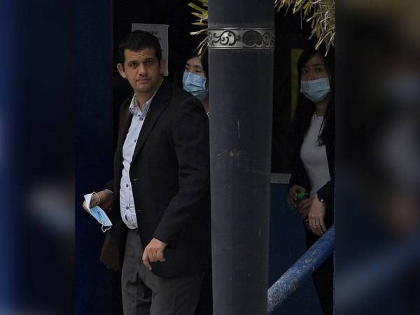 Seorang wartawan (tengah) daripada enam kakitangan stesen penyiaran Al Jazeera bersama tujuh peguam dilihat keluar daripada Ibu Pejabat Polis Bukit Aman untuk dirakam keterangan hari ini. Foto: Bernama