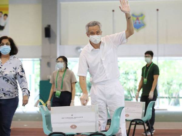 Perdana Menteri, Lee Hsien Loong (tengah) ketika membuang undi di Sekolah Rendah Alexandra hari ini. - Foto: AFP
