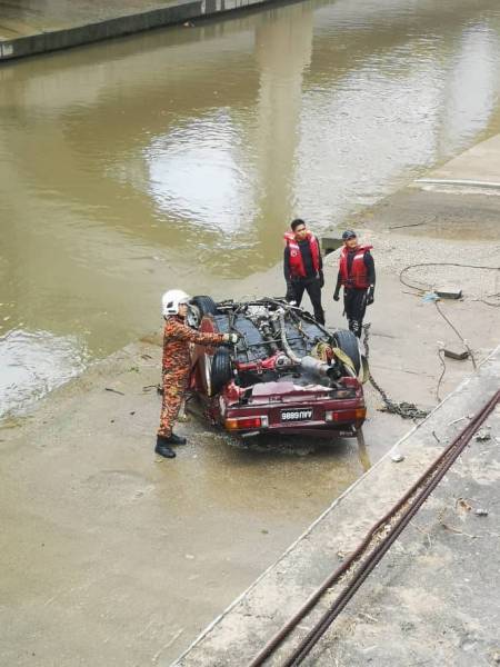 Pasukan bomba menaikkan kereta yang terjunam dalam sungai di Jalan Kuching pagi tadi.