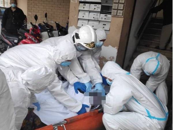 Anggota bomba lengkap dengan sut PPE membawa turun mayat lelaki menggunakan tangga di Kampung Baru, hari ini.