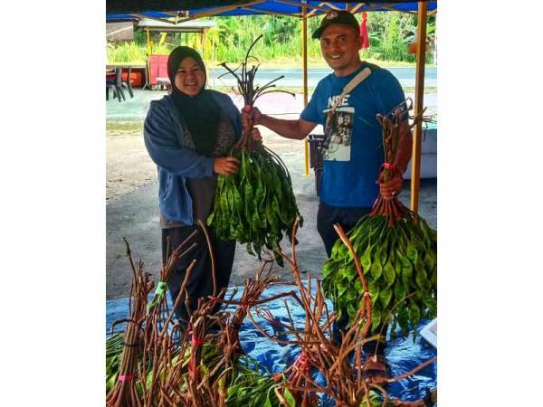 Adzly (kanan) bersama salah seorang pelanggan yang membeli petai dijualnya.