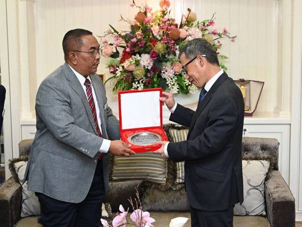 Muhammad Sanusi (kiri) menyampaikan cenderahati kepada Narong sebagai tanda kenang-kenangan.