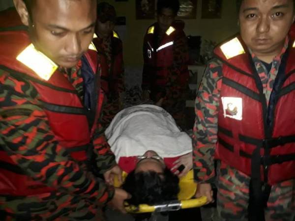 Anggota bomba memindahkan Rosli selepas rumahnya dinaiki air di Taman Orkid, Muar hari ini.