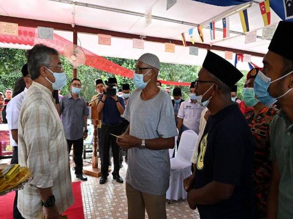 Al-Sultan Abdullah berkenan beramah-mesra dengan mangsa banjir ketika melawat Pusat Pemindahan Banjir Sekolah Kebangsaan Chegar Perah hari ini. Foto: Bernama