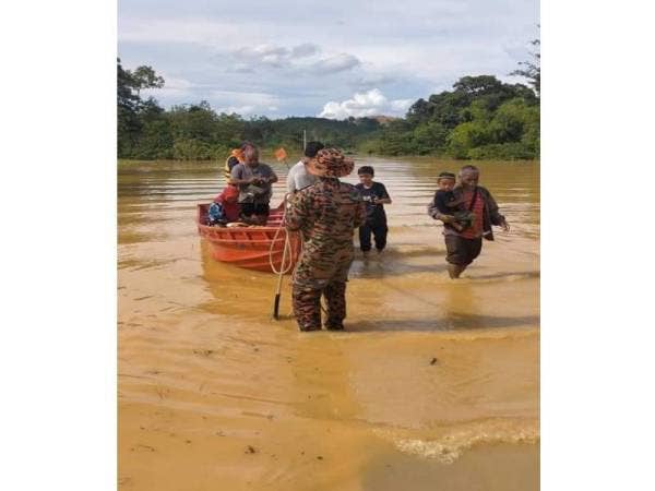 Anggota bomba membantu memindahkan mangsa banjir ke pusat pemindahan. - Foto ihsan bomba