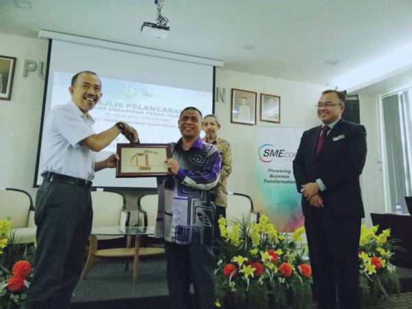 Ketua Pegawai Eksekutif SME Corp Malaysia, Noor Azmi Mat Said (kiri) menyampaikan cenderahati kepada Saarani pada pelancaran Geran Usahawan Perak (Gerup) di Pusat Pembangunan Usahawan PKNP hari ini.