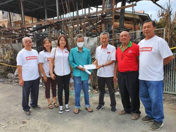 Gan (tiga kanan) menyerahkan bantuan kepada wakil salah sebuah keluarga yang terlibat dalam kebarakan rumah di Jalan Kelochor di sini semalam.