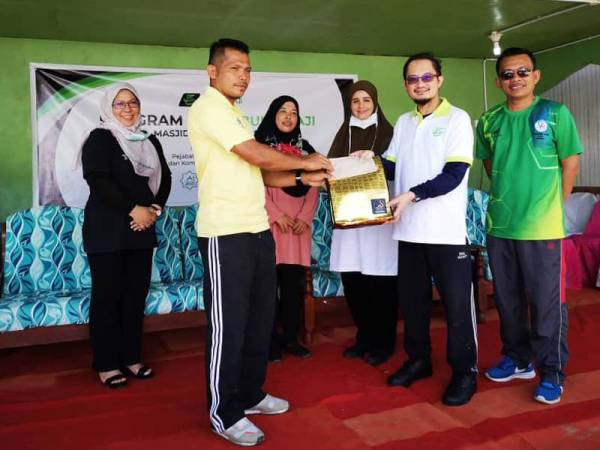 Mustakim Mohamad (dua dari kanan) menyampaikan sumbangan wang tunai kepada Pengerusi Masjid, Mariady Majin ketika program gotong-royong membersih dan membaik pulih Masjid Jamek Al-Hashim, Kota Belud semalam.
