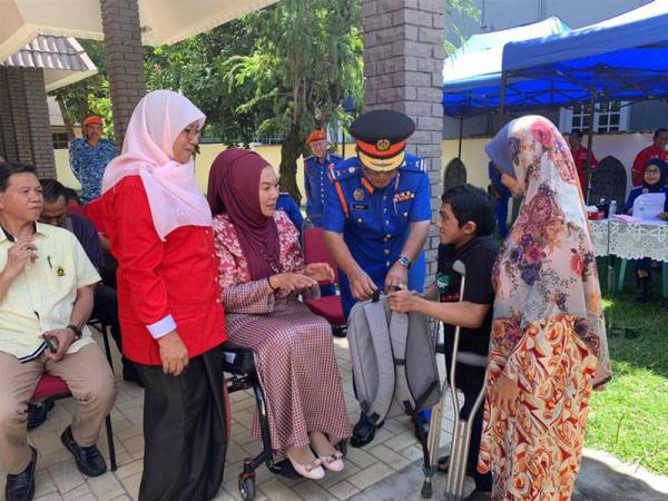 Ras Adiba (dua dari kiri) menyampaikan sumbangan kepada salah seorang peserta OKU yang hadir pada majlis tersebut.