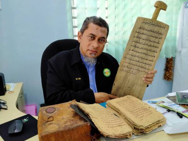Zulkifli menunjukkan papan loq dan al-Quran usang yang digunakan golongan tahfiz di Afrika.