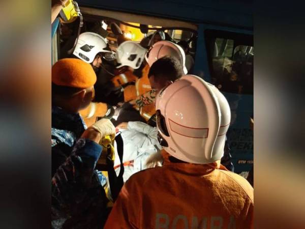 Anggota bomba mengeluarkan mangsa yang tersepit dengan menggunakan peralatan khas dalam nahas di Kampung Chenerai, Kuala Pegang pagi tadi. - Foto JBPM