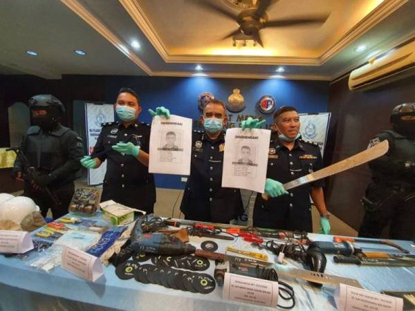 Noorzainy (tengah) menunjukkan gambar dua rakan suspek yang sedang diburu.