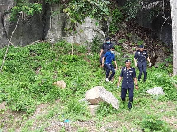 Soffian (depan) meninjau lokasi cebisan tulang dipercayai milik mangsa di kawasan hutan tepi Race Course, Jalan Batu Gantung dua minggu lalu.