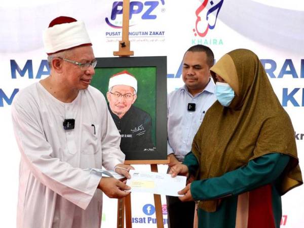 Zulkifli (kiri) menyerahkan surat sumbangan kepada penerima, Hatiah Saari, 41, di Jalan Kampung Pandan Kuala Lumpur kelmarin.