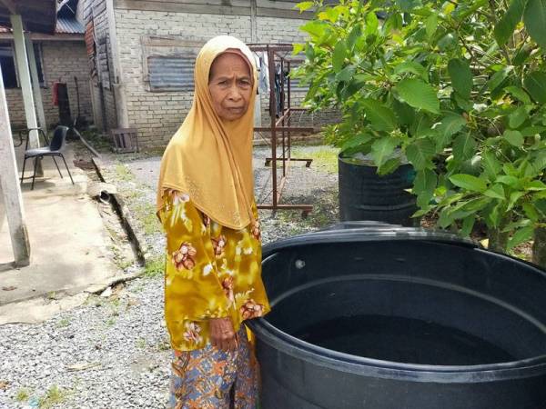 Tibah menanti bekalan air dari lori Sada di hadapan rumahnya.