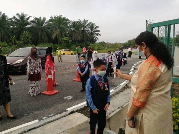 Murid SK Meru Raya, di sini diambil bacaan suhu terlebih dahulu sebelum dibenarkan masuk ke perkarangan sekolah hari ini.