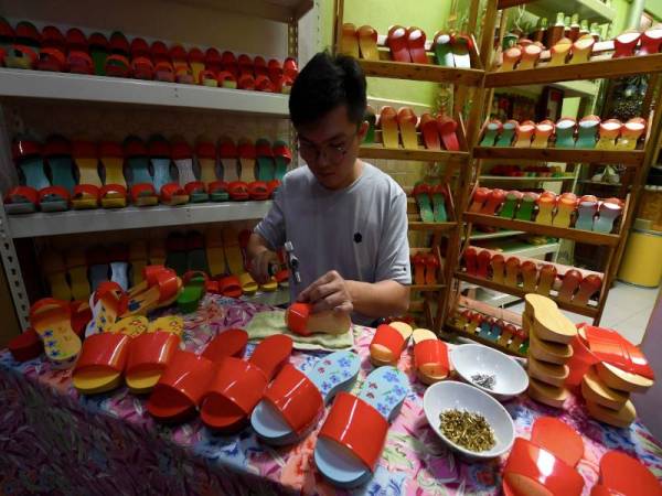 Guan Heng menyiapkan terompah yang ditempah pelanggan di kedainya di Georgetown baru-baru ini.