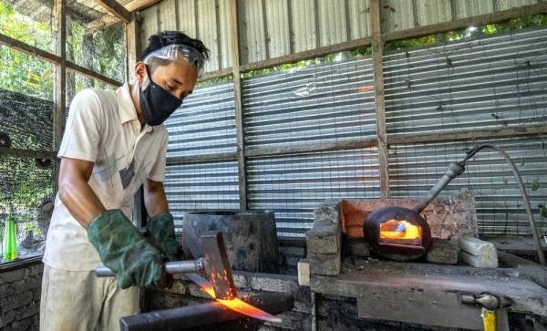 Saiful Azhar mengetuk besi yang telah dipanaskan untuk dijadikan pedang Buaya Berenang di bengkelnya di Kampung Jejulok dekat Slow Machang, Pasir Mas. -Foto Bernama