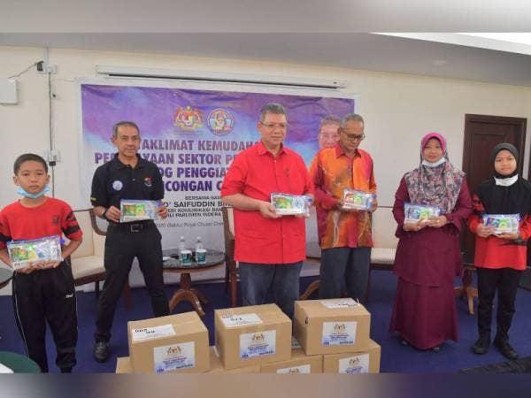Saifuddin (tiga dari kiri) menunjukkan kit penjagaan kebersihan pada majlis Penyerahan Covid-19 Kit kepada Sekolah Menengah Baging dan Sekolah Kebangsaan Cherating hari ini. - Foto Bernama