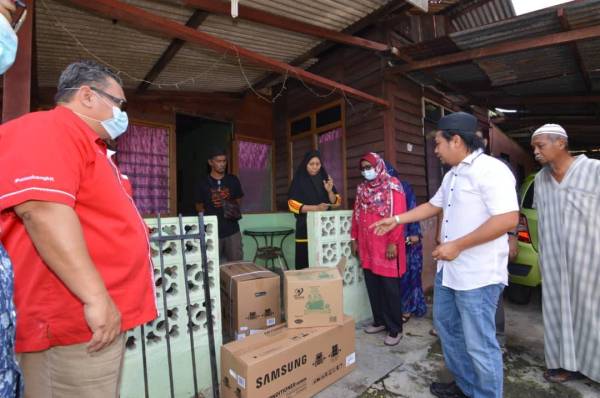 Mohd Asna (dua dari kanan) menyampaikan sumbangan pendingin hawa kepada Shuhada (bertudung hitam).