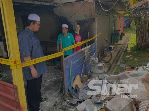 Adani (kanan) membawa Mujibur Rahman melawat dapur rumah yang terbakar.