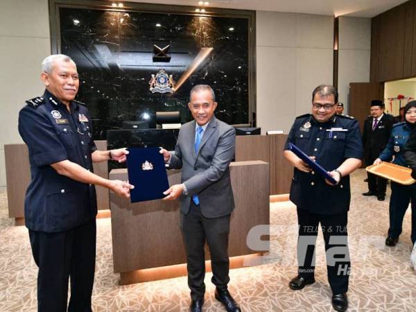 Adib Azhari (tengah) menyerahkan dokumen MoU kepada Razimi selepas menandatangani MoU antara MBJB, polis dan Jabatan Pengangkutan Jalan di Bangunan MBJB, Johor Baharu, hari ini.