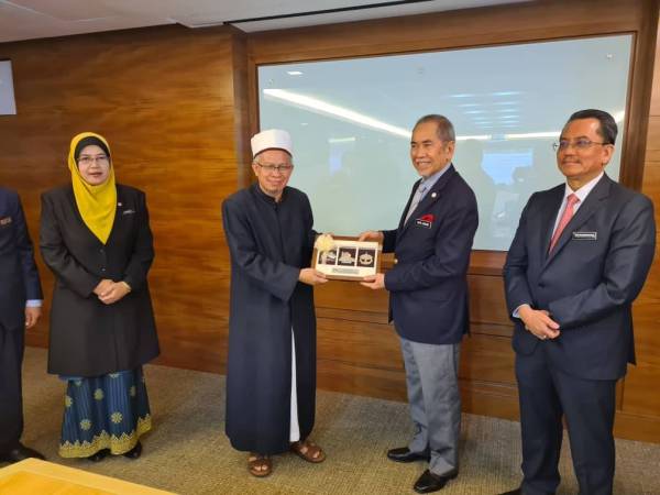Wan Junaidi (dua dari kanan) menyerahkan cenderahati kepada Menteri di Jabatan Perdana Menteri (Hal Ehwal Agama), Senator Datuk Seri Dr Zulkifli Mohamad Al Bakri pada majlis pemeteraian kerjasama strategik antara MEDAC dan Jakim di Ibu kota kelmarin.