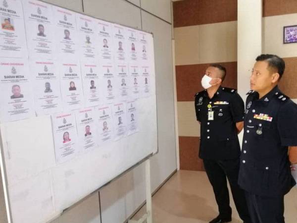 Mohd Khairiel (kanan) dan Timbalannya, Deputi Superintendan Mohd Hafiz Muhammad Nor melihat gambar 19 individu yang dikehendaki polis daerah Jempol.