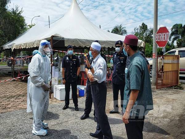 Dr Mohd Hayati mendengar penerangan daripada petugas kesihatan yang menjalankan saringan di klinik Kesihatan Napoh, Jitra hari ini.