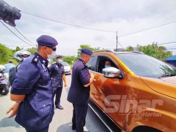 Chunng Tsaur (dua dari kiri) bertanya sesuatu kepada pengguna jalan raya yang melalui sekatan jalan raya di Pekan Napoh hari ini.